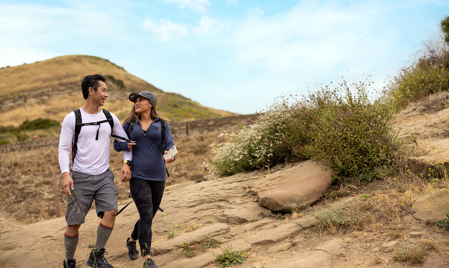 A man and woman hiking on a dirt trail.